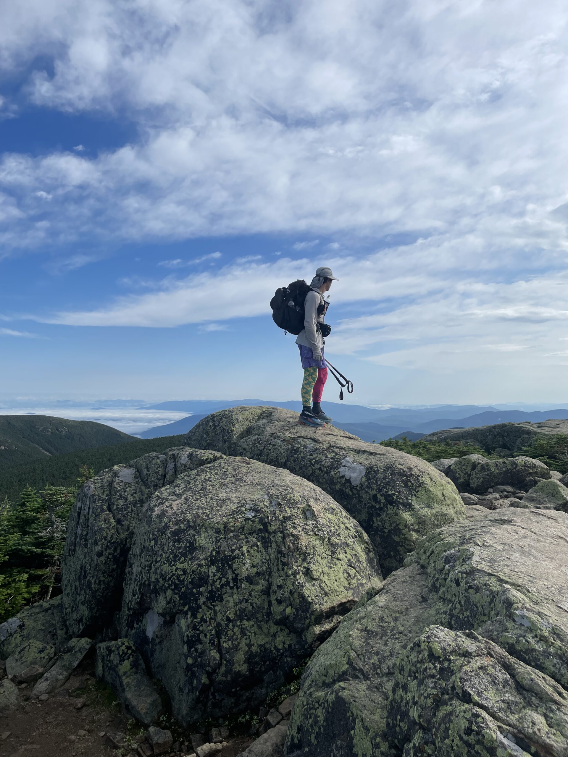 Appalachian Trail backpacker standing on a rock crop in Western Maine